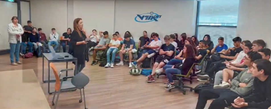 מורה מדברת מול קבוצת תלמידים הישובים בחצי מעגל בכיתה