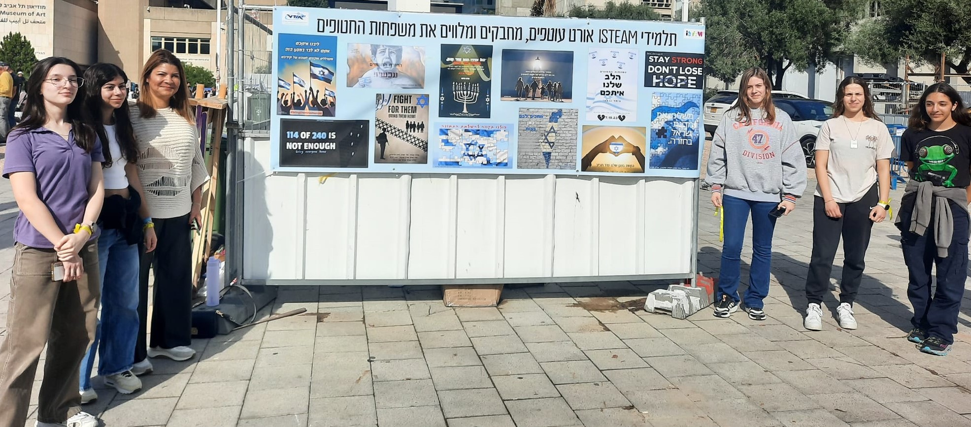 תלמידים עומדים סביב שלט כרזות